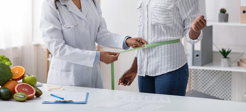 Cropped of female doctor measuring patient body with tape at clinic, panorama