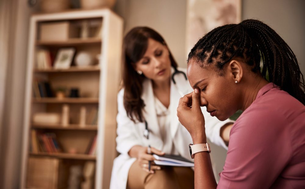 An African-American female patient having a hard period in life and talking with a female psychologist.
