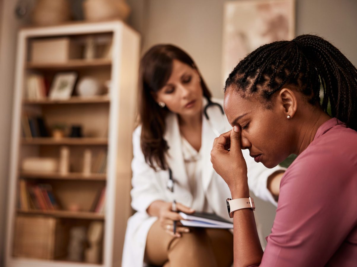 An African-American female patient having a hard period in life and talking with a female psychologist.